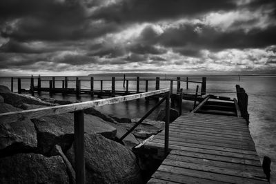 Pier over sea against cloudy sky