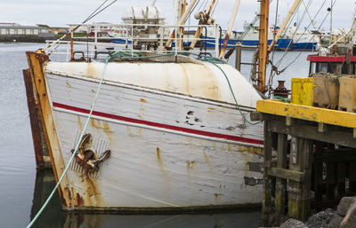 The photo shows the bow of a moored, rusting 