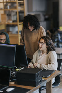 Multiracial business colleagues discussing over computer at desk in office