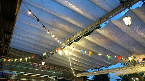 Low angle view of illuminated light bulbs hanging from ceiling