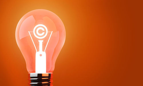 Illuminated light bulb against orange background