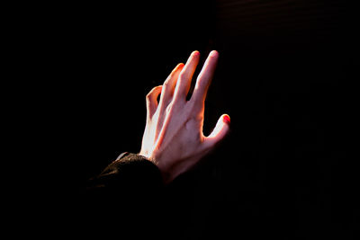 Cropped hand of woman reaching black background