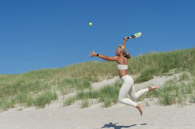 Full length of man jumping against clear sky