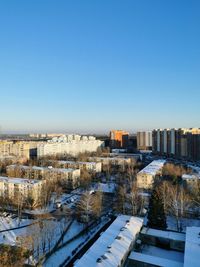 High angle view of snow covered buildings against blue sky