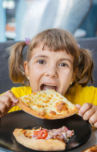 Cute girl eating pizza at table in restaurant