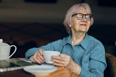 Smiling senior woman holding coffee cup at cafe
