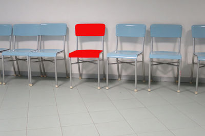 Empty chairs on tiled floor against wall
