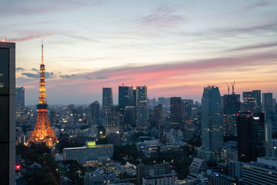 Illuminated buildings in city against sky during sunset