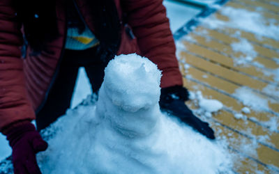 Midsection of person making snowman