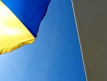 Low angle view of yellow flag against clear blue sky