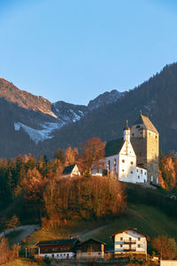 Buildings by mountains against clear sky