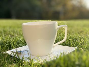 Close-up of coffee cup on grassy field