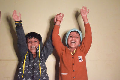 Portrait of happy friends standing against wall