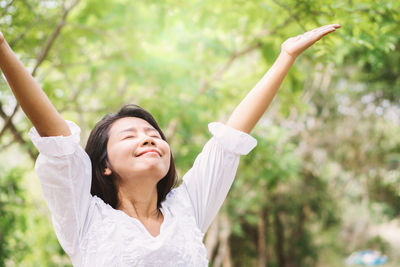 Woman with arms raised against tress