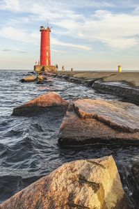 Lighthouse by sea against sky