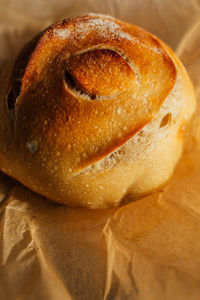 Freshly baked round loaf of homemade sourdough bread on brown parchment paper