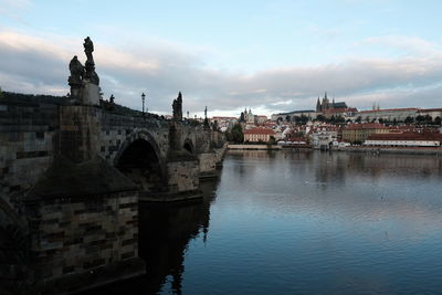 Arch bridge over river in city against sky