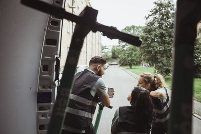 Delivery man sharing smart phone with female coworkers