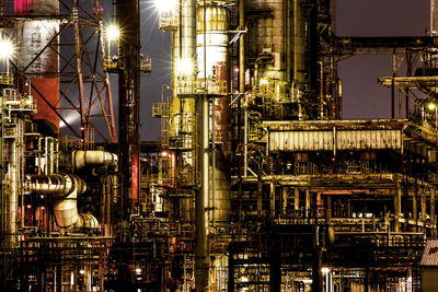 Illuminated oil industry against sky at night