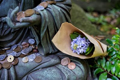 Close-up of statue with flowers and coins