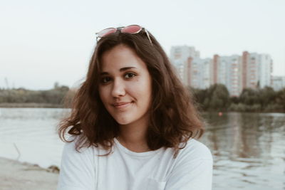 Portrait of young woman against lake in city