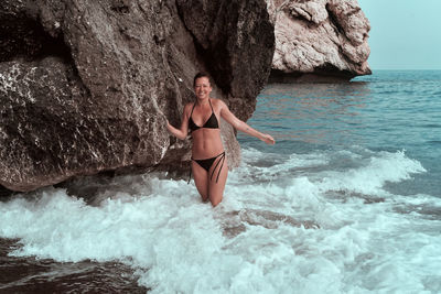 Portrait of young woman on rock by sea