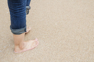Low section of woman standing on sand