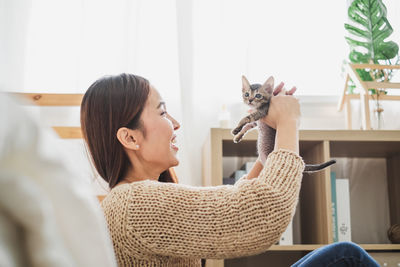 Woman playing with kitten at home