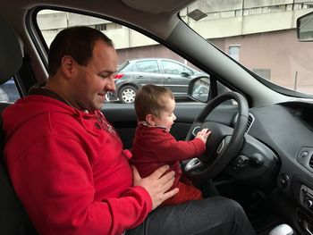 Side view of happy father with son on driving seat