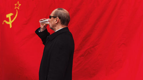 Side view of man drinking beer against former ussr flag