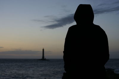 Rear view of silhouette man looking at sea against sky