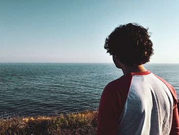 Rear view of woman looking at sea against clear sky