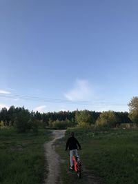 Rear view of man riding motorcycle on field against sky