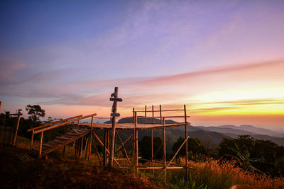 Cross on field against sky during sunset