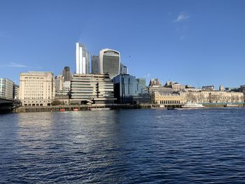 Buildings by river against blue sky