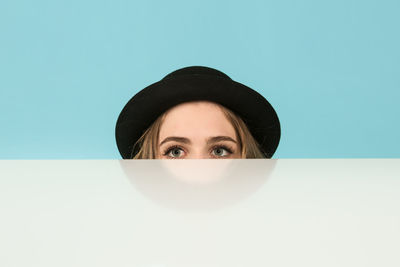 Portrait of young woman against blue background