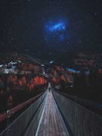 Illuminated footbridge against sky at night