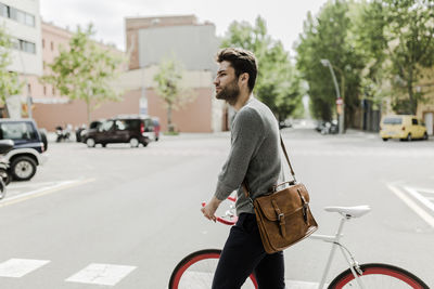 Young man pushing his bike on a street