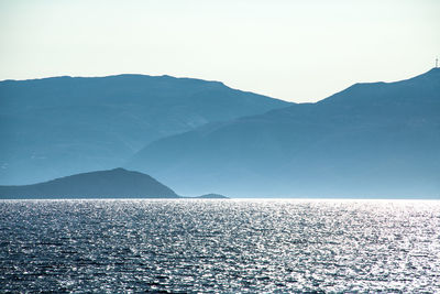 Scenic view of sea and mountains against clear sky