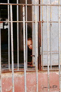 Portrait of boy seen through metal building