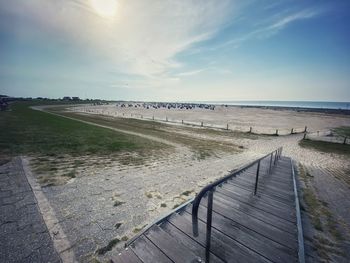 Boardwalk leading towards sea against sky