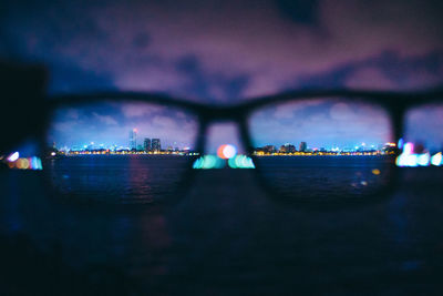 Close-up of illuminated cityscape by river at night