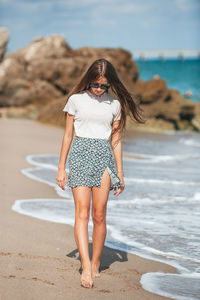 Full length of young woman standing at beach