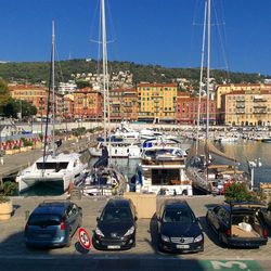 Boats moored at harbor in city against sky