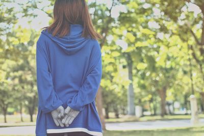 Rear view of woman standing against trees