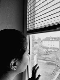 Close-up of boy looking through window at home