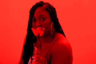 Portrait of beautiful braided black young woman against red background