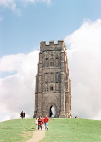 People in front of historical building against cloudy sky