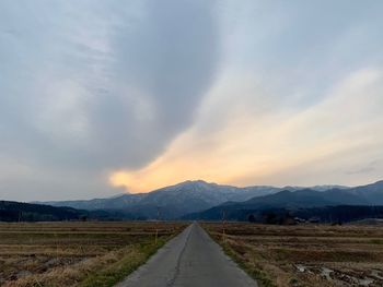 Road leading towards mountains against sky