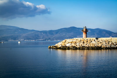 Lighthouse by sea against sky